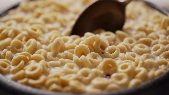 Spoon Grabs Cereal Rings with Milk From Ceramic Bowl alt