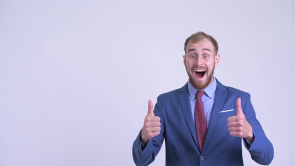 Happy Bearded Businessman Pointing Up and Looking Surprised