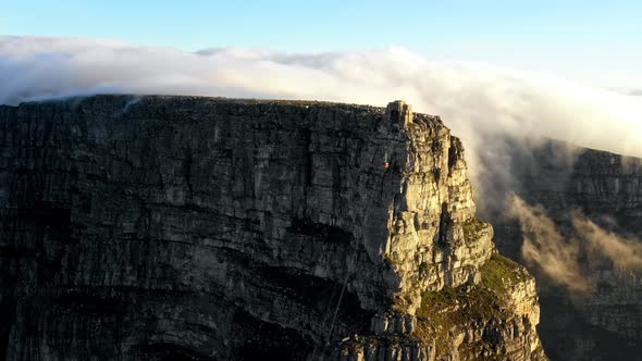 Drone shot of cable car descending from a mountain surrounded by clouds