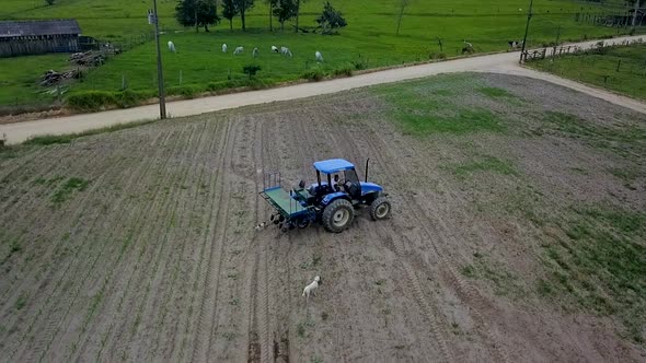 A tractor turns around in a field after having cultivated a row into the dirt AERIAL VIEW alt
