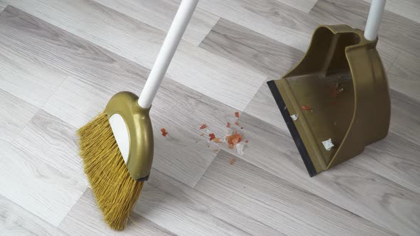 A Broom Sweeps Dirt Off the Floor Into a Scoop