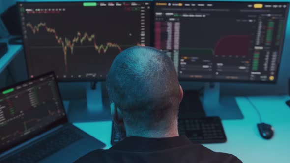 Mature Male Stock Market Trader or Broker Analyzing Graphs on Multiple Computer Screens alt