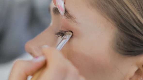 Professional Makeup Artist Is Applying Eye Shadows To Upper Eyelid of Model Eye