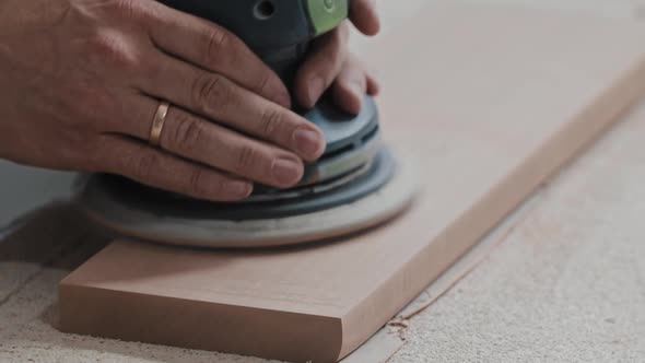 Carpentry Works  Worker Makes the Top Surface of a Wooden Detail Softer with a Grinding Machine alt