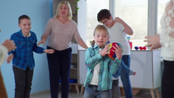 Boy with Down Syndrome Has Fun Playing Ball Lesson in Inclusive School During Therapy for Children alt