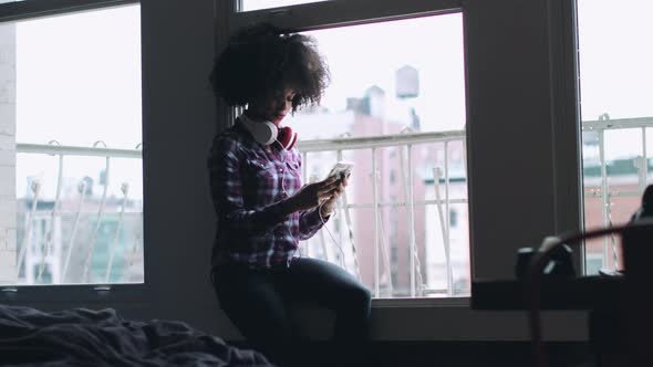 Afro American Female with smart phone, wearing headphones