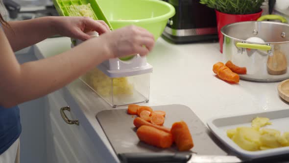 Woman Cooking Salad in the Kitchen Using a Vegetable Chopper with Container Chop and Slice Boiled alt