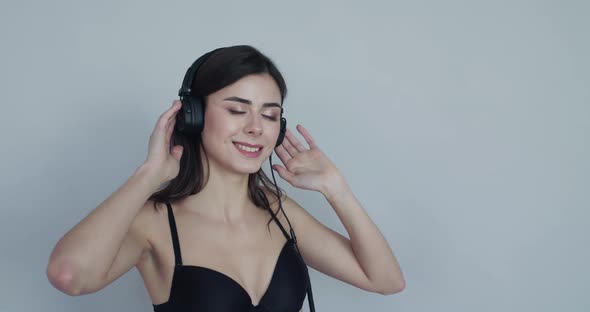 Girl with Headphones on Touching the Earcups Swaying Her Head and Smiling alt