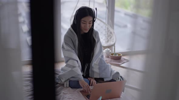 Wide Shot Portrait of Charming Asian Freelancer in Comfortable Home Office Conferencing Online on alt