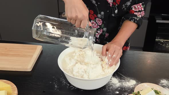 Adding water to flour in bowl, cooking dough for pizza alt