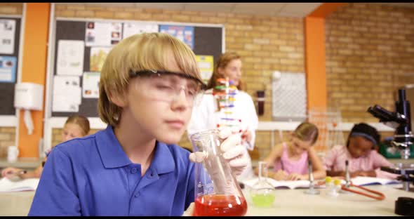 Schoolboy doing chemical experiment in laboratory alt