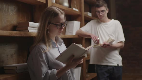 Young Smart Couple in Eyeglasses Reading Books at the Library alt