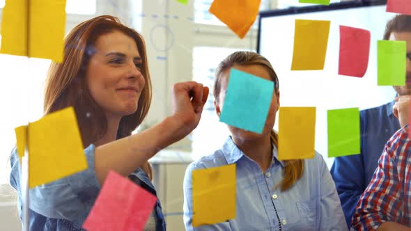Business executives discussing over sticky notes alt