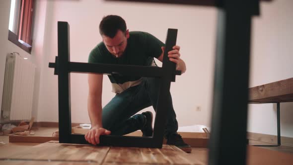 Assembling DIY Table. Man Installing Modern Metal Table Leg To Wooden Table Top. static alt