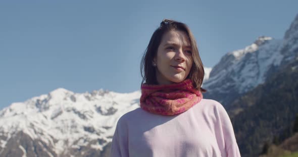 Portrait of Young Woman Looking at Camera and Smiling on Background of Mountains