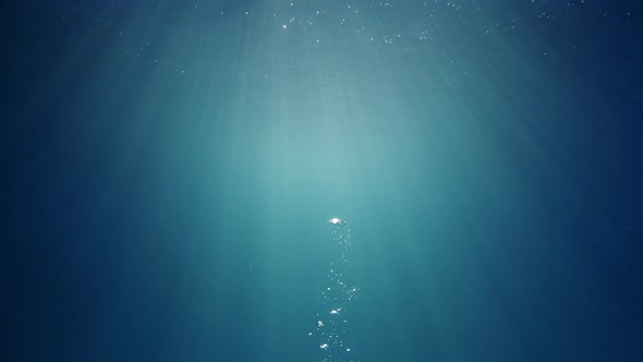Sunlight beams shining through the deep crystal clear blue-turquoise colored water causing a beautif alt