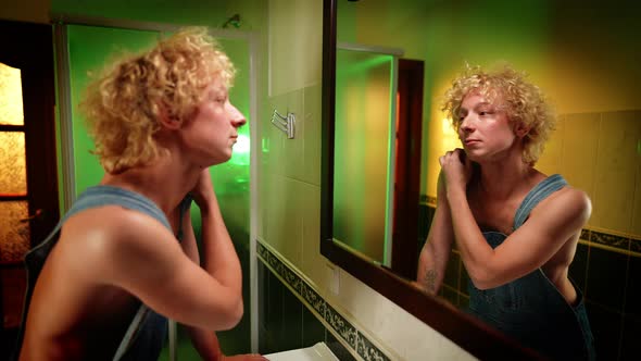 Male Caucasian Queer Person Admiring Reflection in Mirror in Bathroom alt