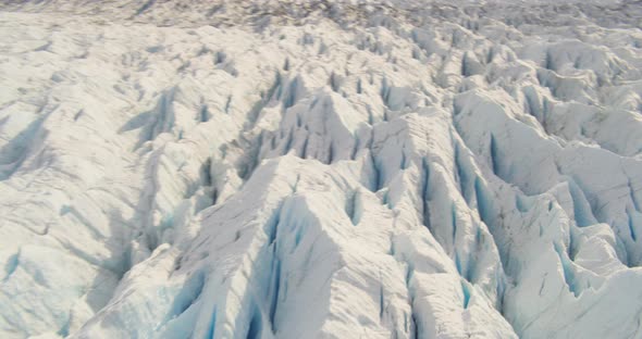 Aerial footage across snowy Alaskan mountaintops and snowy tundra, tilt down to vast valley, drone h alt