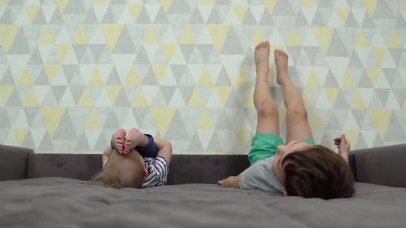 Two Children Are Lying on the Bed Upside Down