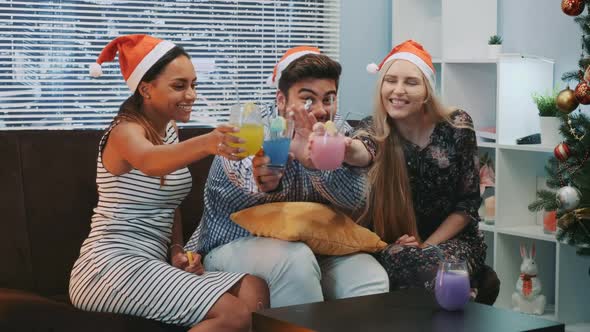 Beautiful Young People in Santa Hats Making Cheers and Blowing Party Whistle alt