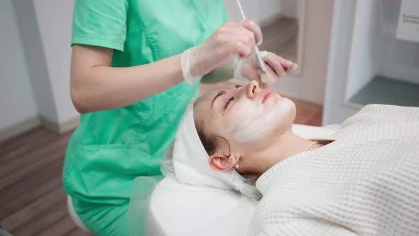 Female Beautician Makes Face Rejuvenation and Cleansing Procedure for Girl alt