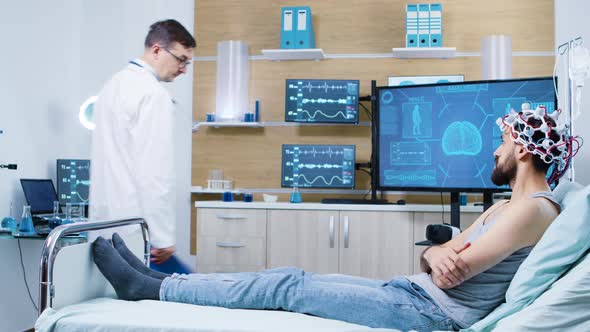 Doctor in a Brain Research Laboratory Checking on Patient Sitting on Bed alt