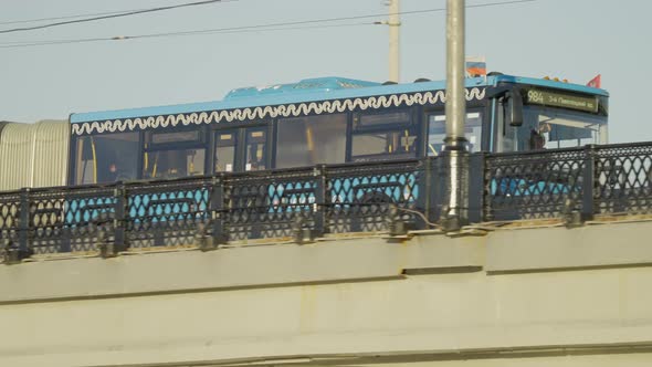 An Elongated Modern Blue Bus Passes Through a Bridge in the Center of Moscow