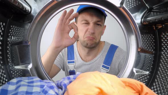 Washing machine repair worker looks inside mababan and shows class. alt