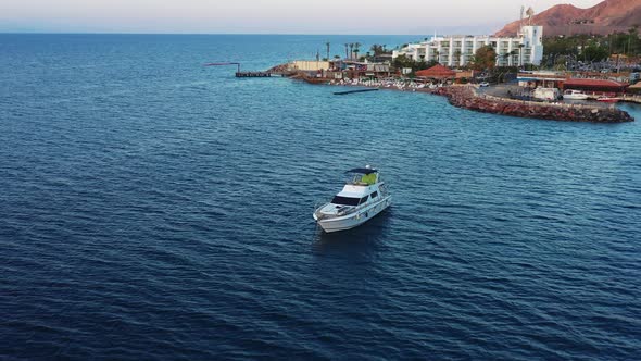 Flying over a luxury motor yacht and towards a modern boutique, Red Sea beach resort in Eilat Israel alt
