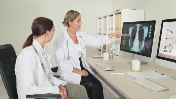 Female Doctors Discussing Chest X Ray on Computer alt