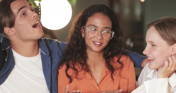 Crop View of Young Cheerful Friends Laughing and Talking While Having Good Time in Cafe. Group of alt