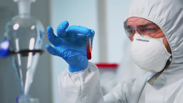 Scientist Holding Blood Sample Wearing Protection Suit alt