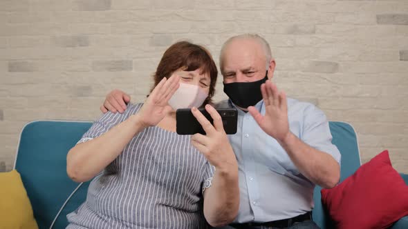 Senior Couple Talking on Video Chat with Their Children and Wearing a Medicinal Mask alt