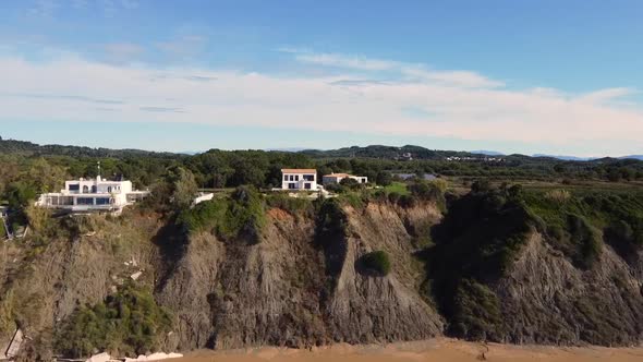 Breathtaking daytime aerial drone flight offshore coastline waves to a luxury villa on a malibu clif alt