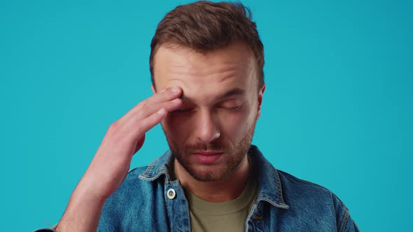 Young Handsome Man Standing Over Isolated Blue Background Suffering From Headache