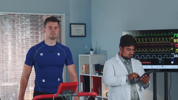 Mixed Race Doctor Performing Stress Test While the Athlete Walking on Treadmill alt