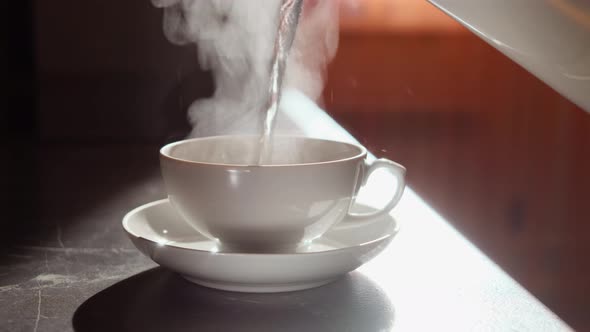 White cup of tea with hot aromatic tea, which gives off wonderful steam.