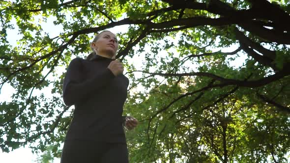 Fit Woman Running Under Trees alt