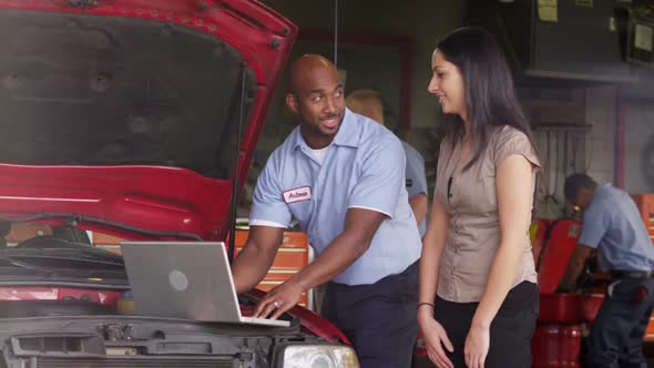 Auto repairman shows customer laptop computer alt