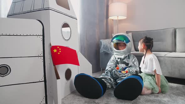 Asian Kids Play in the Living Room at Home a Boy in an Astronaut Costume Sitting on the Floor with alt