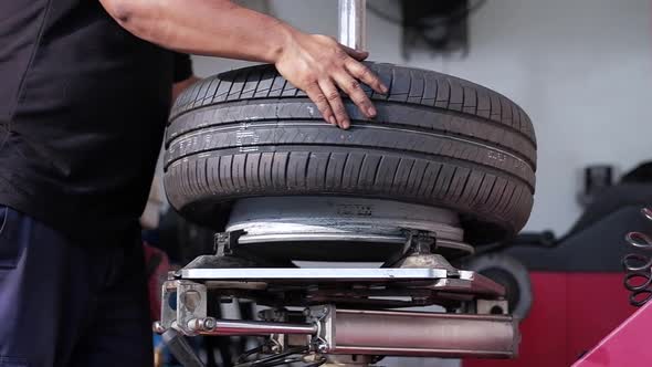 Tire Replacement concept. Mechanic Working his Job with Wheel in Garage