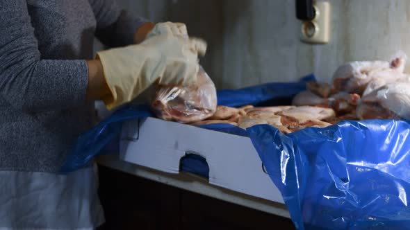 Closeup View of Hands in Gloves Packing Chicken Legs From a Box Into Individual Plastic Bags alt
