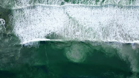 Aerial - Waves rolling out, white-wash with sandy bottom disturbed, ascending drone shot alt