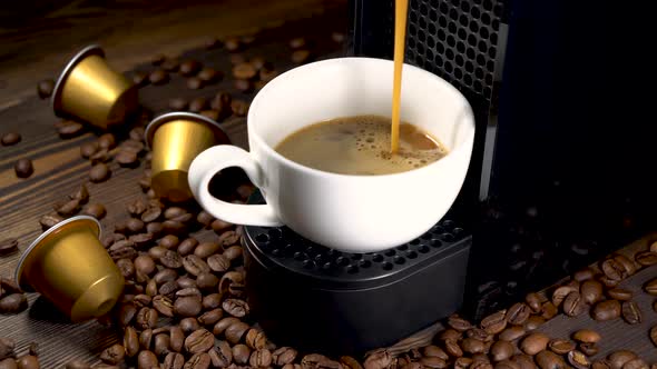 Automatic coffee machine with coffee capsules or pods pouring espresso drink.