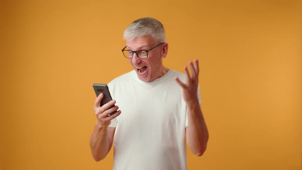 Elderly Retired Man Looking at Telephone Screen Celebrating Getting Message with Good News