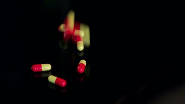 Closeup of Pills Falling on Black Table Slow Mo alt