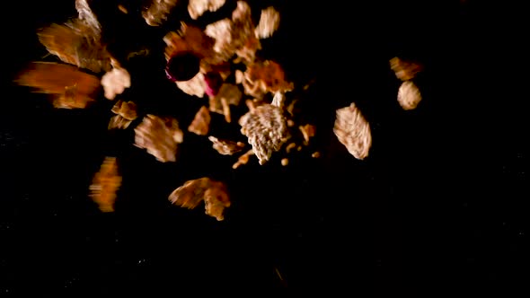Berries and Cornflakes falling from the dark in the light and hitting on the ground in slow motion. alt