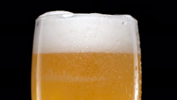 Close Up Light Beer is Pouring Into Glass on Black Background alt