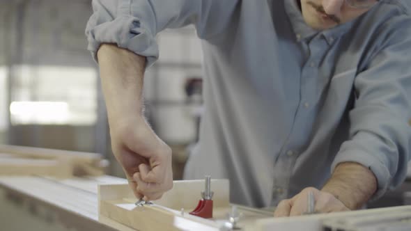 Carpenter Fixing Piece of Wood with Clamps for Cutting on Table Saw alt
