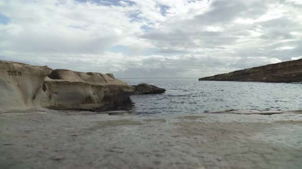 Low Angle Shot of St Peters Pool Stone Beach Shoreline with Mediterranean Sea in Background